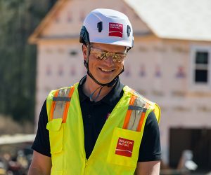 Person smiling in safety glasses and a Type II safety helmet, showcasing modern construction safety gear.